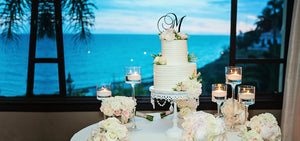 tiered white wedding cake with monogram cake topper on white chandelier cake stand for ocean view wedding